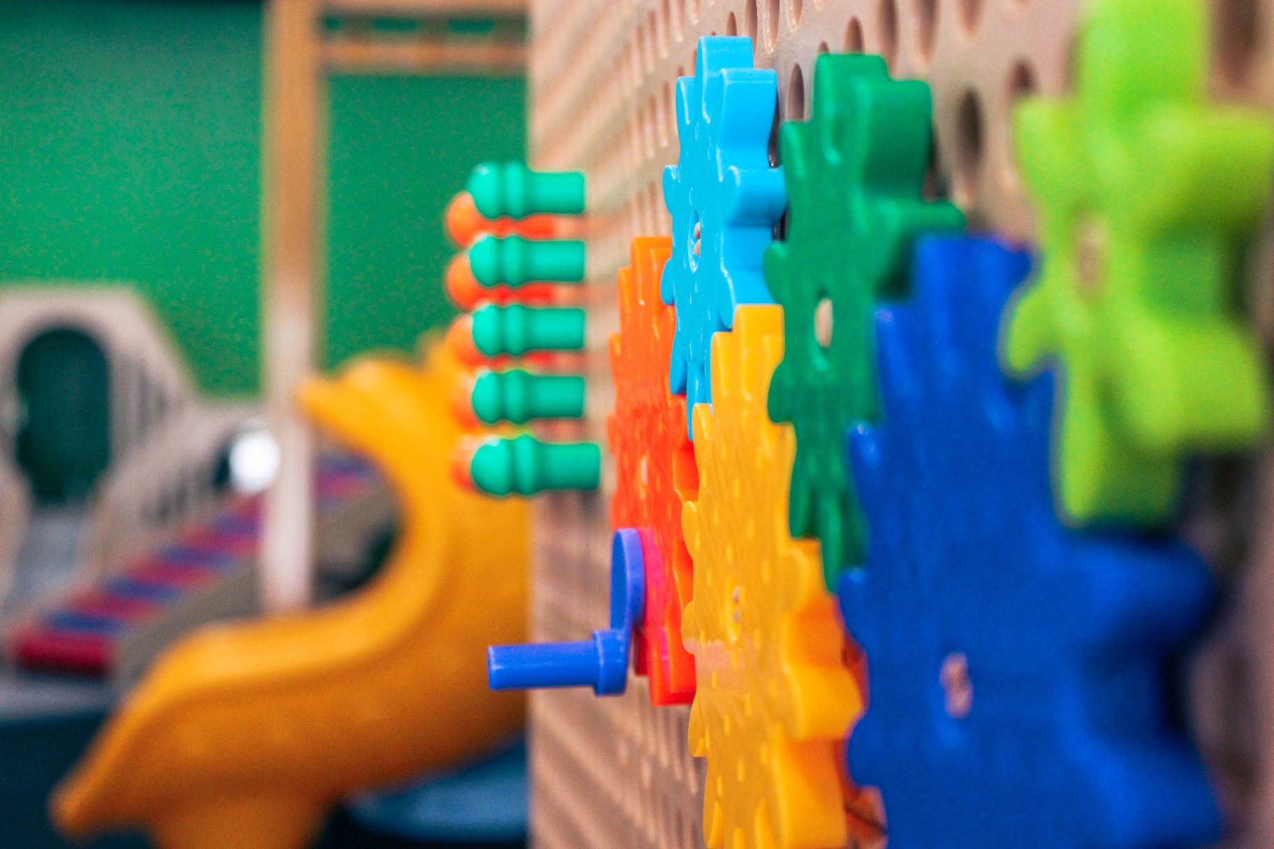 Close-up of a colorful gears and pegs activity wall in the New Braunfels fine motor room