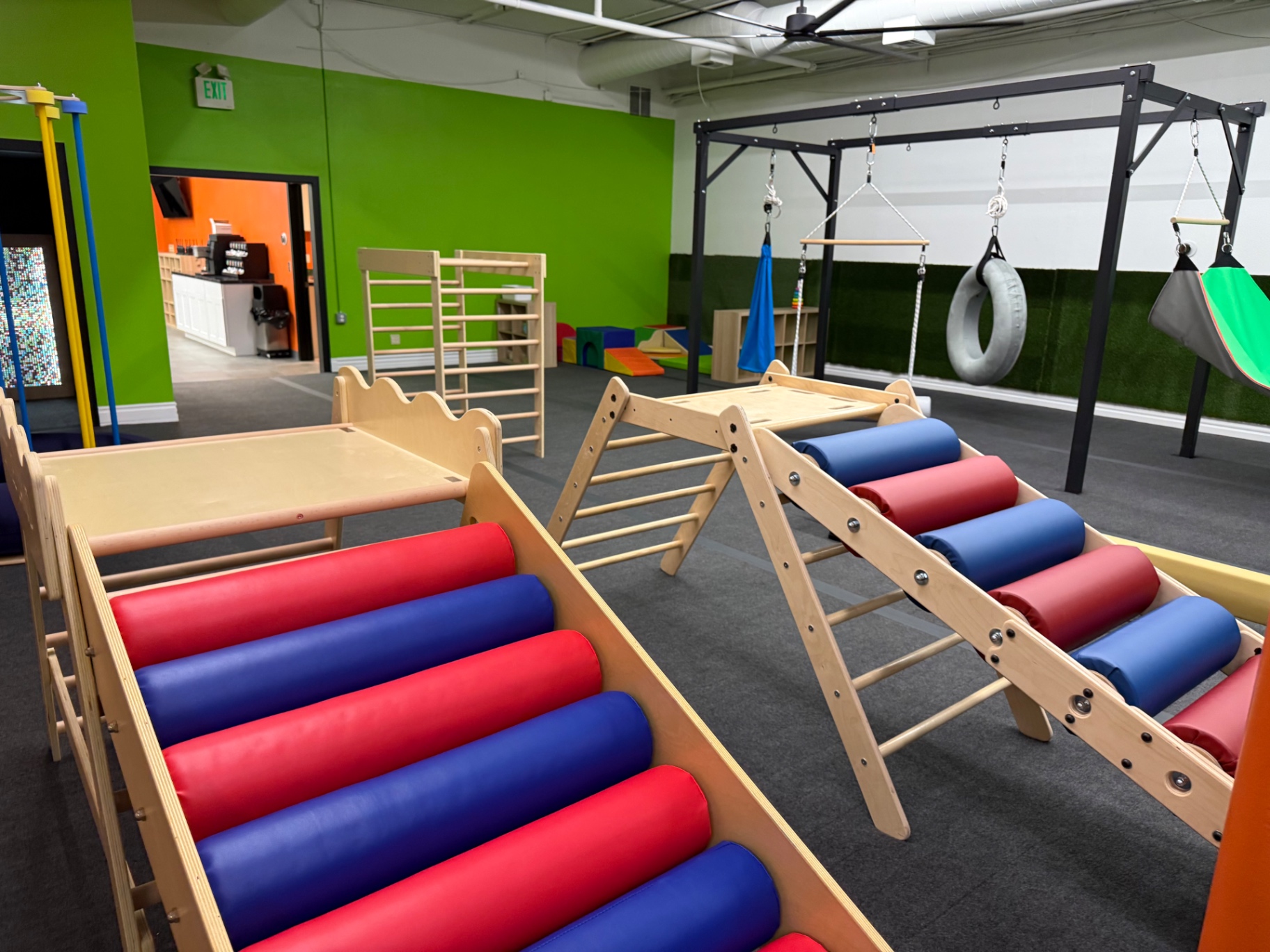 Red and blue roller ramps and Pikler triangles in the Arcadia play gym