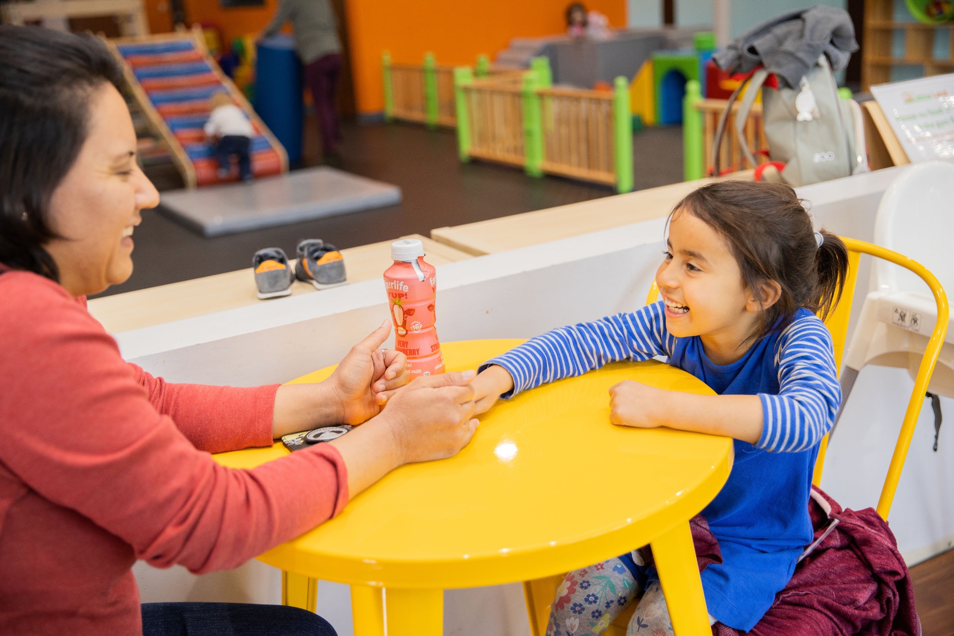 Mom and daughter laughing together at a bright yellow snack table
