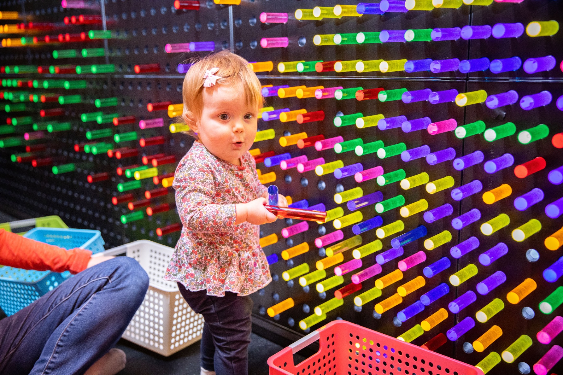 Toddler exploring a colorful peg light wall in the Little Land sensory room