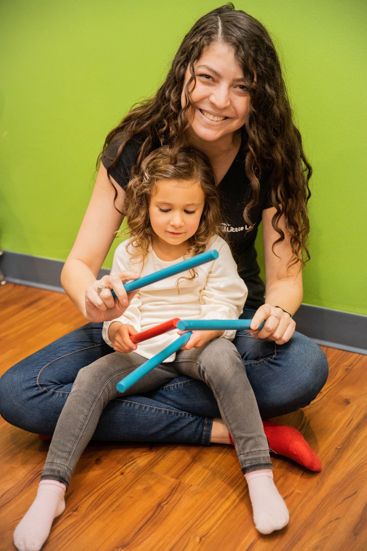Music teacher and child playing together with rhythm sticks