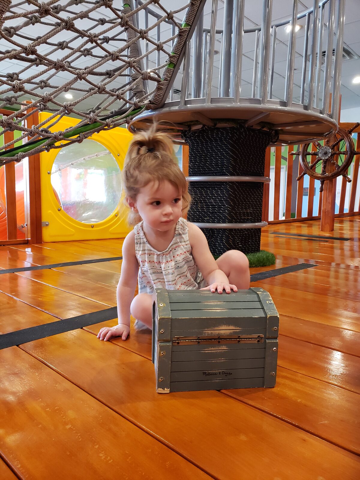 Toddler in a pirate costume climbing across the rope bridge play structure