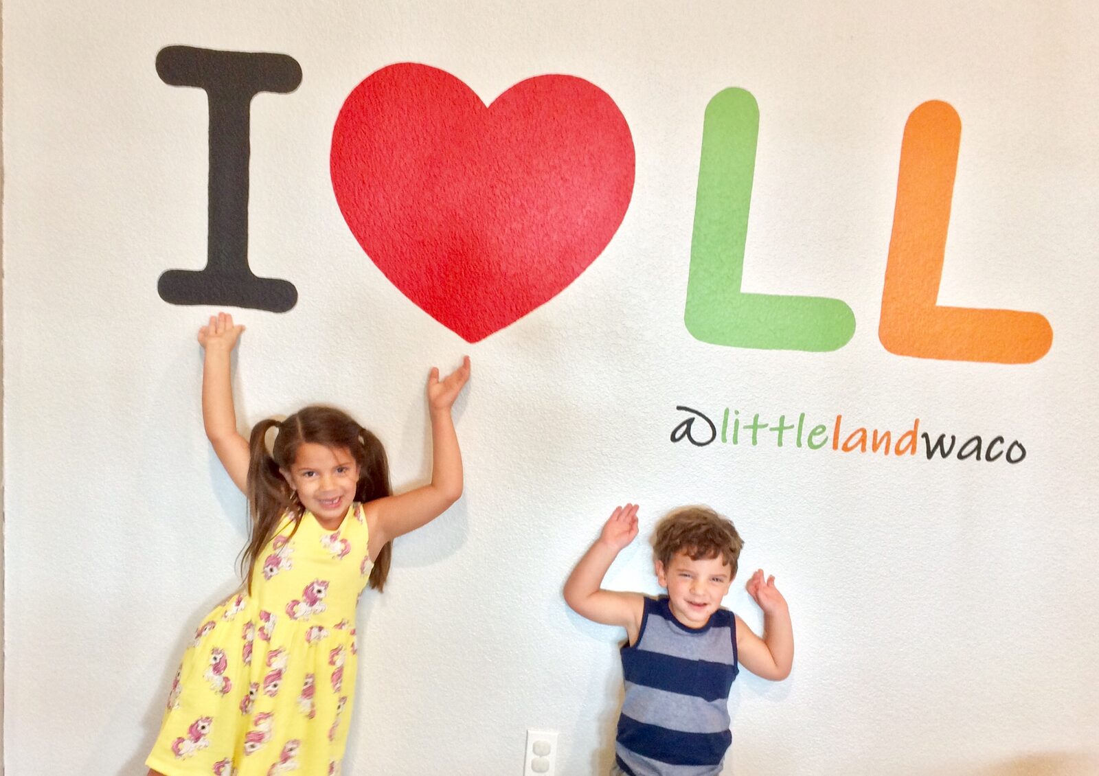 Two young brothers in helmets and safety harnesses on the indoor ropes course